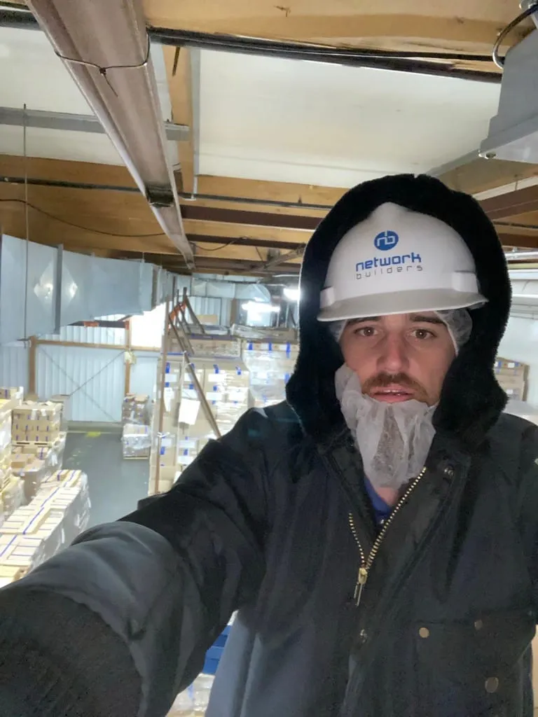 An NBIT engineer in cold-weather gear inside a client's frozen-storage warehouse